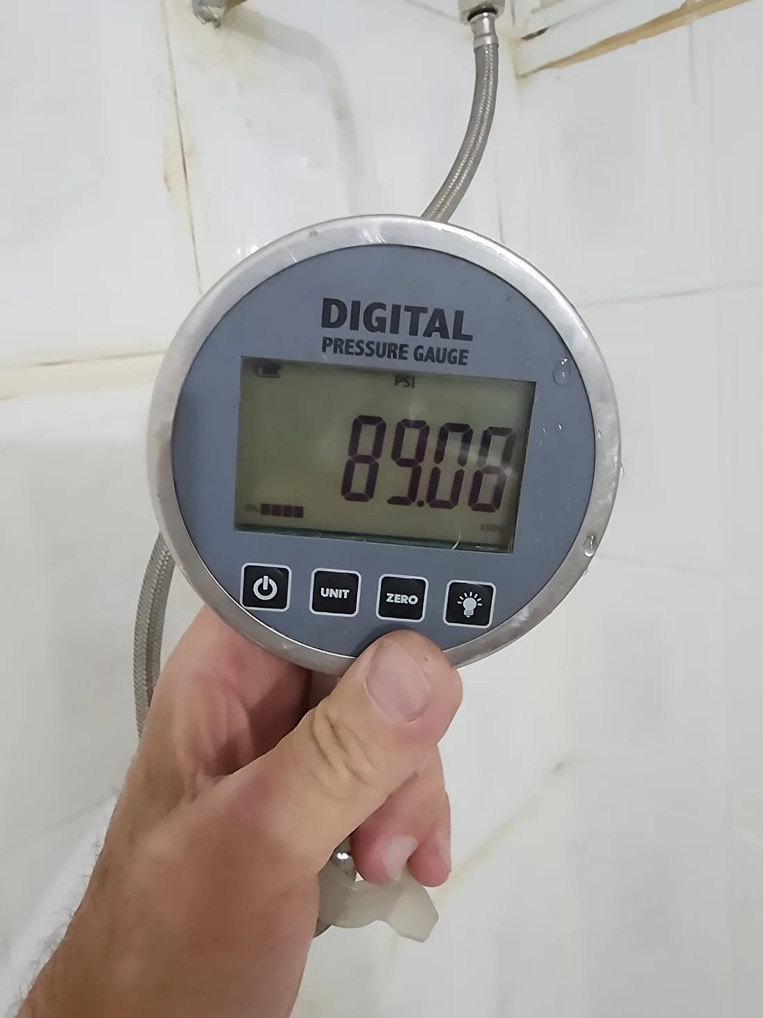 מד לחץ דיגיטלי מחובר לצנרת מציג 89 PSI בבדיקת לחץ